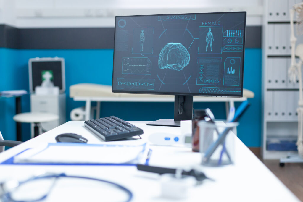 Medical office with computer displaying digital brain scan secured by healthcare cybersecurity services